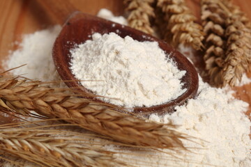 Wooden spoon with flour and wheat ears