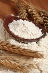 Wooden spoon with flour and wheat ears