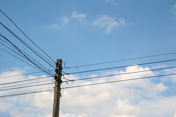 High voltage electric lines background bright sky and white clouds