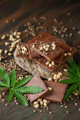 Vegan Chocolate with pine nut, cannabis leaves and seeds on wooden background. Healthy take of break