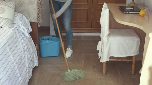Woman with a mop cleaning floor at home