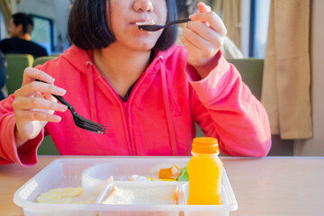 Girl in red sweater eating breakfast in box