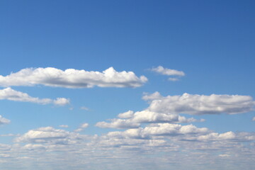 White fluffy clouds on a background of blue sky in summer. The concept of weather and climate.