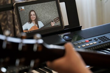 Female musicians rehearsing online during self-isolation due to pandemic COVID-19. Girl with guitar online.