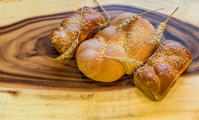 Traditional grey bread with ears of wheat on wooden background