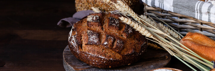 Concept of homemade bread, natural farm products, domestic production. Healthy and tasty organic food. Close up,  dark black background. Copy space for text. Banner