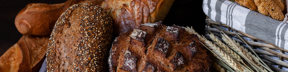 Concept of homemade bread, natural farm products, domestic production. Healthy and tasty organic food. Close up,  dark black background. Banner