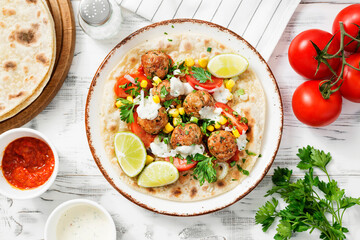 Tortilla with grilled meatball, corn and fresh salad. top view