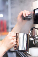 Fototapeta na wymiar Coffee shop worker preparing coffee on steam espresso coffee machine. Barista Warming Milk In Metal Jug With Steam Of Coffee Machine. vertical photo