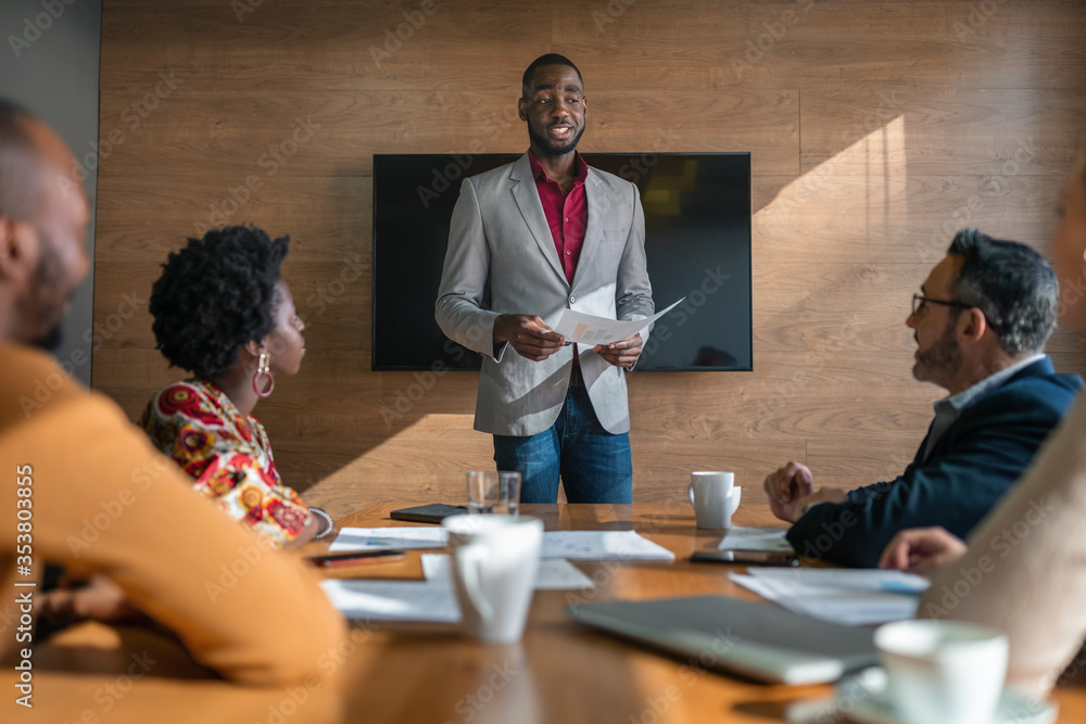 Wall mural manager going over paperwork with staff during a boardroom meeting