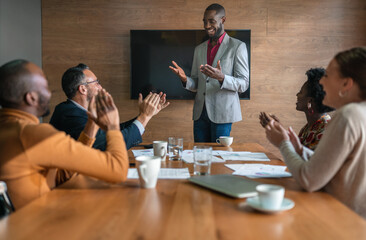 Diverse businesspeople clapping after a presentation in an office