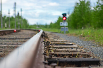 Railroad, closeup of part of the rail and sleepers, in the background the semaphore is lit in red. High quality photo