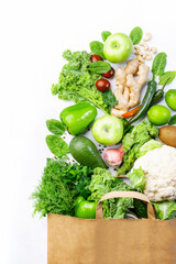 Healthy green vegan vegetarian food in full paper bag, vegetables and fruits on white background. Shopping food supermarket, raw detox diet and clean eating concept. Healthy food background