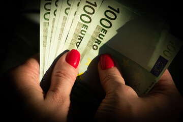 Several hundred Euro banknotes in the hands of a woman with a beautiful manicure. Euro close-up in...