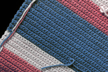 Crochet texture close-up of blue, red and beige threads, top view. Hand made concept. Abstract background with copy space
