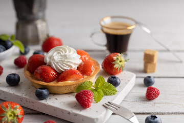 Homemade dessert strawberry pie with raspberry's and blue berry's and a coffee.