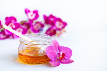depilation and beauty concept - sugar paste or wax honey for hair removing with wooden waxing spatula sticks on flower background