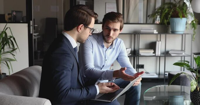 Two successful businessmen handshake agree on business service integrity network growth at office meeting. Happy adviser and client using laptop shaking hands supporting partnership solution concept.