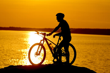 Fototapeta na wymiar Silhouette of a sporty cyclist in helmet on a bike. Active Lifestyle Concept.