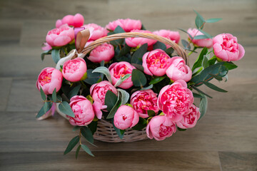 bouquet of pink peonies in a basket on the floor. 