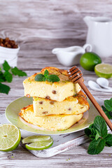 Cottage cheese casserole with raisins and mint, lime slices on a plate on a wooden table