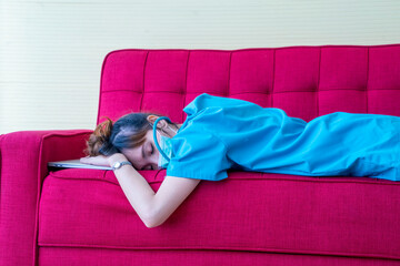 Obraz premium The Asian doctor worked so hard to take care of herself until she slept with the laptop on the red sofa, the doctor's resting room in the hospital.