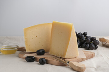 Homemade cheese on wooden plate at light background.