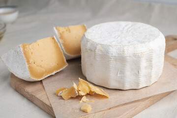 Homemade cheese on wooden plate at light background.