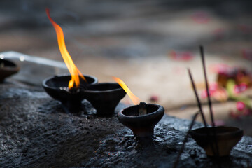Oil in little pots alight with lit incense sticks, an offering to the gods, Bali.Asia