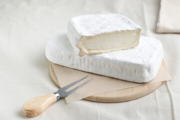 Homemade cheese on wooden plate at light background.