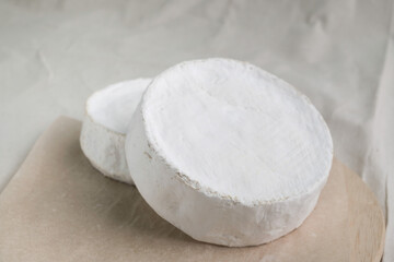 Homemade cheese on wooden plate at light background.