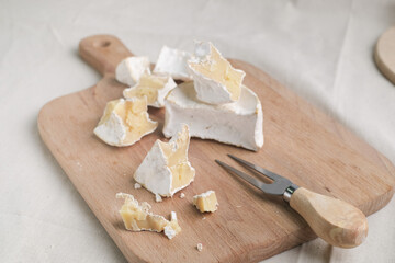 Fototapeta premium Homemade cheese on wooden plate at light background.