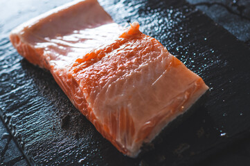Half a fresh salmon steak close-up lies on a wet stone stand