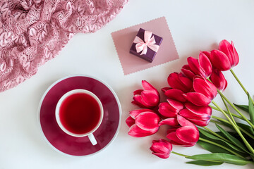 A bouquet of pink tulips with gifts on a white background with a Cup of tea, Holiday concept, Greetings on international women's day