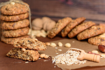 homemade oatmeal cookies with dates, peanuts, coconut shavings on a wooden background, macro close-up. broken cookies in the foreground