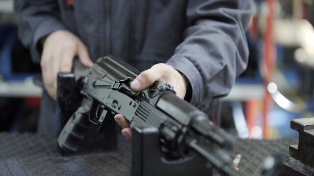 Factory assembly of a Kalashnikov assault rifle. Close up of charging rifle. AK47 loading. Factory worker hand charging machine gun. Factory worker collects the AK-47.