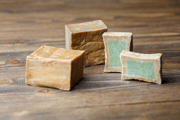 Two bars and slices of traditional aleppo organic laurel soap on a brown wooden background.