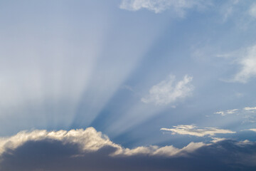 The background of sun rays over clouds. Dark and light clouds.