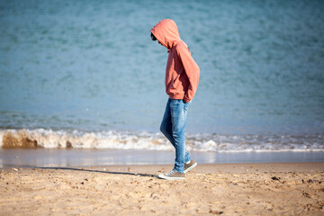 Adolescente paseando melancólico por la playa