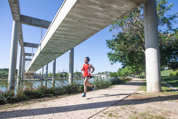 Hombre joven practicando running en el parque junto a un lago