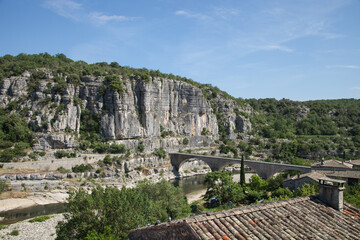 Fototapeta na wymiar Pont enjambant la rivière Ardèche au pied des falaises de Balazuc