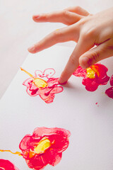 Child girl painting flowers with colorful hands and finger