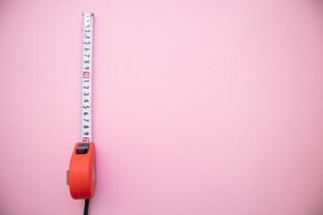 Single red tape measure on pink background. Top view with free copy space