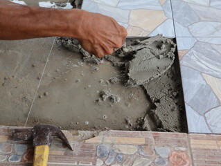 The worker's hands were tiling the bathroom floor with a trowel.