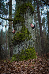 man hugging a tree covered with moss
