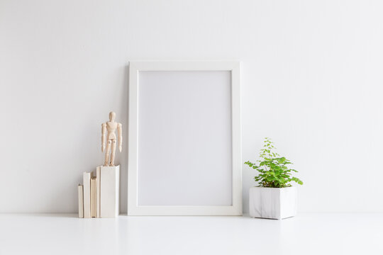 White desk with photo frame, office supplies, boxes and fresh natural leaf in design vase.