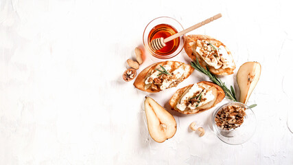 Obraz na płótnie Canvas Toast with cheese, pear, honey and nuts. Delicious breakfast or snack with brie camembert cheese on a light background, top view