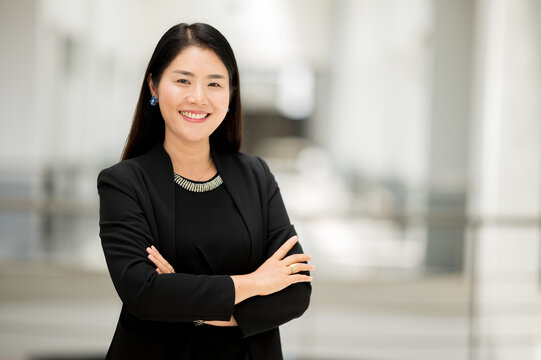 Portrait Working Woman Asian Wearing A Black Suit, Smiling, Crossed Hands Looking At The Camera With Confidence