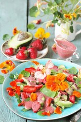 salad with nasturtium flowers and leaves with strawberries and avocados. dressed with strawberry vinaigrette or strawberry dressing with poppy seeds.