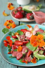 salad with nasturtium flowers and leaves with strawberries and avocados. dressed with strawberry vinaigrette or strawberry dressing with poppy seeds.